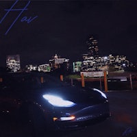 a tesla model s parked in front of a city at night