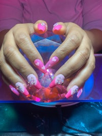 a woman with pink nails holding a pink crystal