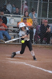 a girl swinging a bat at a ball