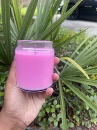 a person holding a pink candle in front of a palm tree
