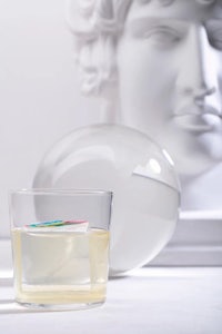 a glass of water next to a statue of a man