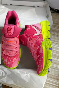 a pair of pink and green nike shoes in a box