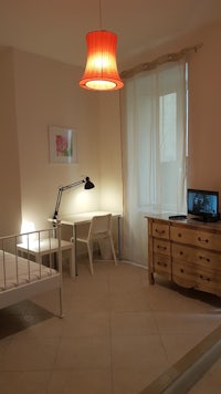 a small room with a bed, desk and tv