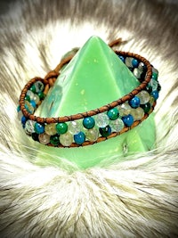 a bracelet with green and blue beads on a furry surface
