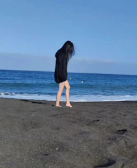 a girl standing on a beach with the ocean in the background