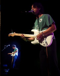 a man is playing a guitar in front of a microphone