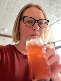 a woman wearing glasses is drinking a drink