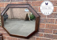 a wooden octagonal mirror on a brick wall
