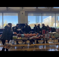 a group of people standing around a table full of basketballs
