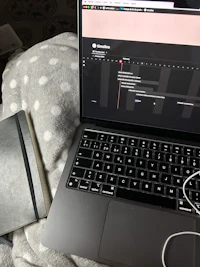 a laptop on a bed next to a notebook