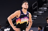 a basketball player standing on the court with his hands on his hips