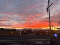 a red and orange sunset over a parking lot