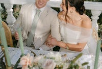 a bride and groom laughing at their wedding table