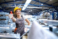 a female worker giving a thumbs up in a factory