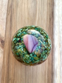 a green and pink stone ball on a wooden table