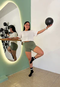 a woman standing in front of a mirror with a ball in her hands