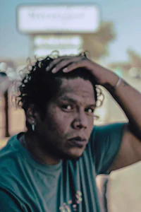 a man with curly hair sitting on the side of the road