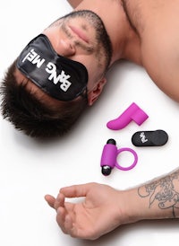 a man is laying on a bed with a purple eye mask