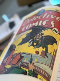 a comic book is open with a batman on the cover