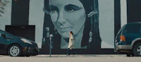 a woman walks past a mural of a woman on a wall
