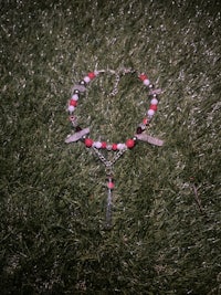 a necklace with red and white beads laying on the grass