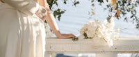 a bride and groom holding a bouquet by the water