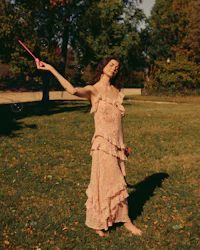 a woman in a pink dress is holding a kite