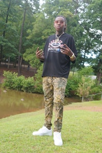 a man in a camouflage sweatshirt standing in a grassy area