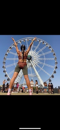 a woman is standing in front of a ferris wheel