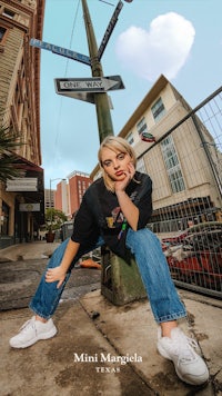 a woman is posing in front of a street sign