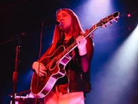 a girl playing an acoustic guitar on stage