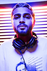 a man wearing headphones in front of a neon wall
