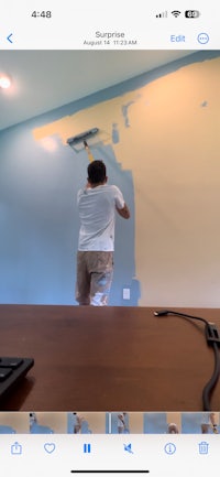 a man is painting a wall in a room