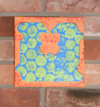 an orange and blue piece of art hanging on a brick wall