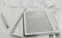 an e-reader and a pen on a bed