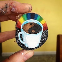 a person holding up a piece of wood with a coffee cup on it
