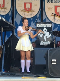a girl in a yellow dress playing a violin on stage
