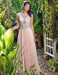 a beautiful woman in a pink dress standing in a garden