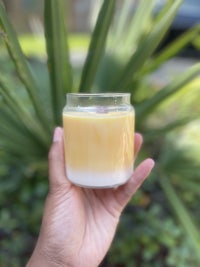 a person holding a candle in front of a palm tree