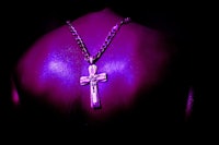 the back of a man with a purple cross necklace
