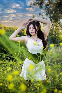a woman in a white dress posing in a field of yellow flowers