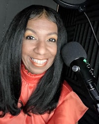 a woman smiling in front of a microphone
