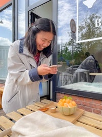 a woman looking at her phone while sitting at a table