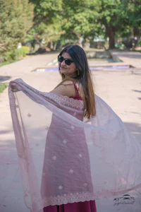a woman wearing a pink shawl and sunglasses