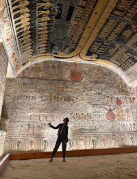 a man standing in front of an egyptian painting
