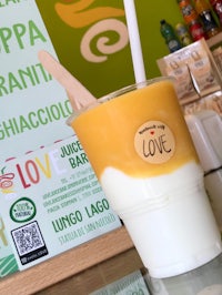 a cup of orange juice is sitting on a table next to a sign