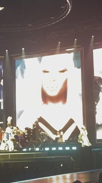 a large screen showing a woman on stage