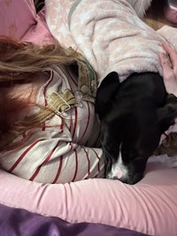 a woman is laying on a bed with a dog