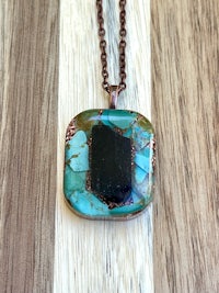 a necklace with a turquoise stone and a copper chain