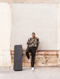 a man leaning against a wall with a skateboard